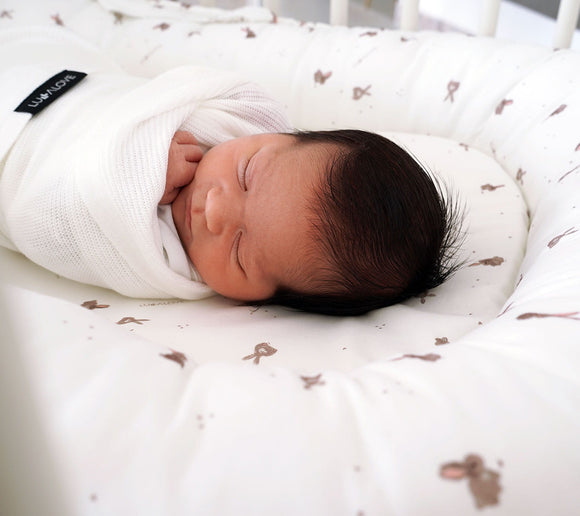 Baby swaddled in a Lullalove white knitted swaddle